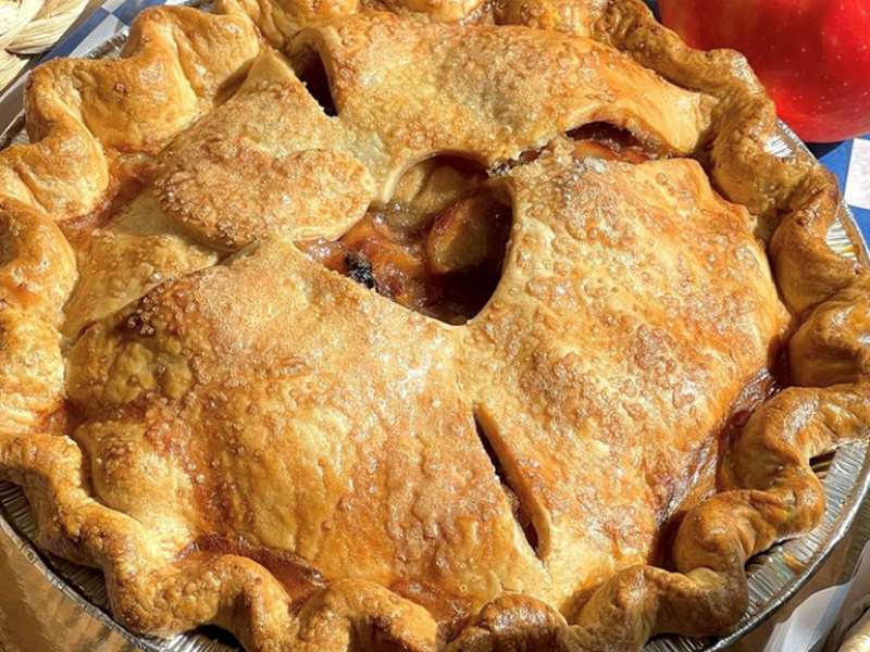 An apple with pie with golden flaky crust and sunlit honeycrisp apples